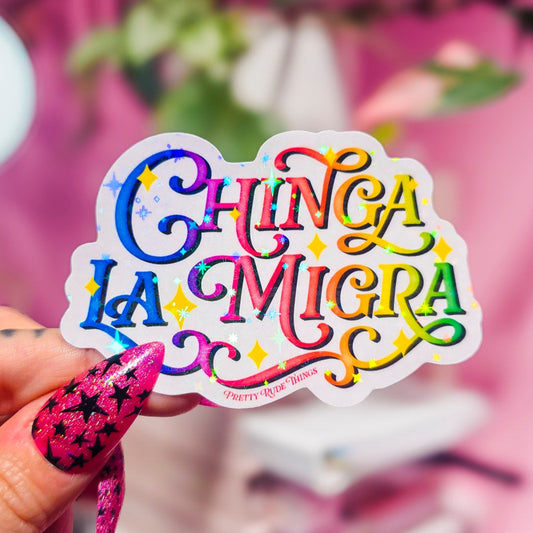 Hand holding a colorful sticker with text against a blurred indoor background