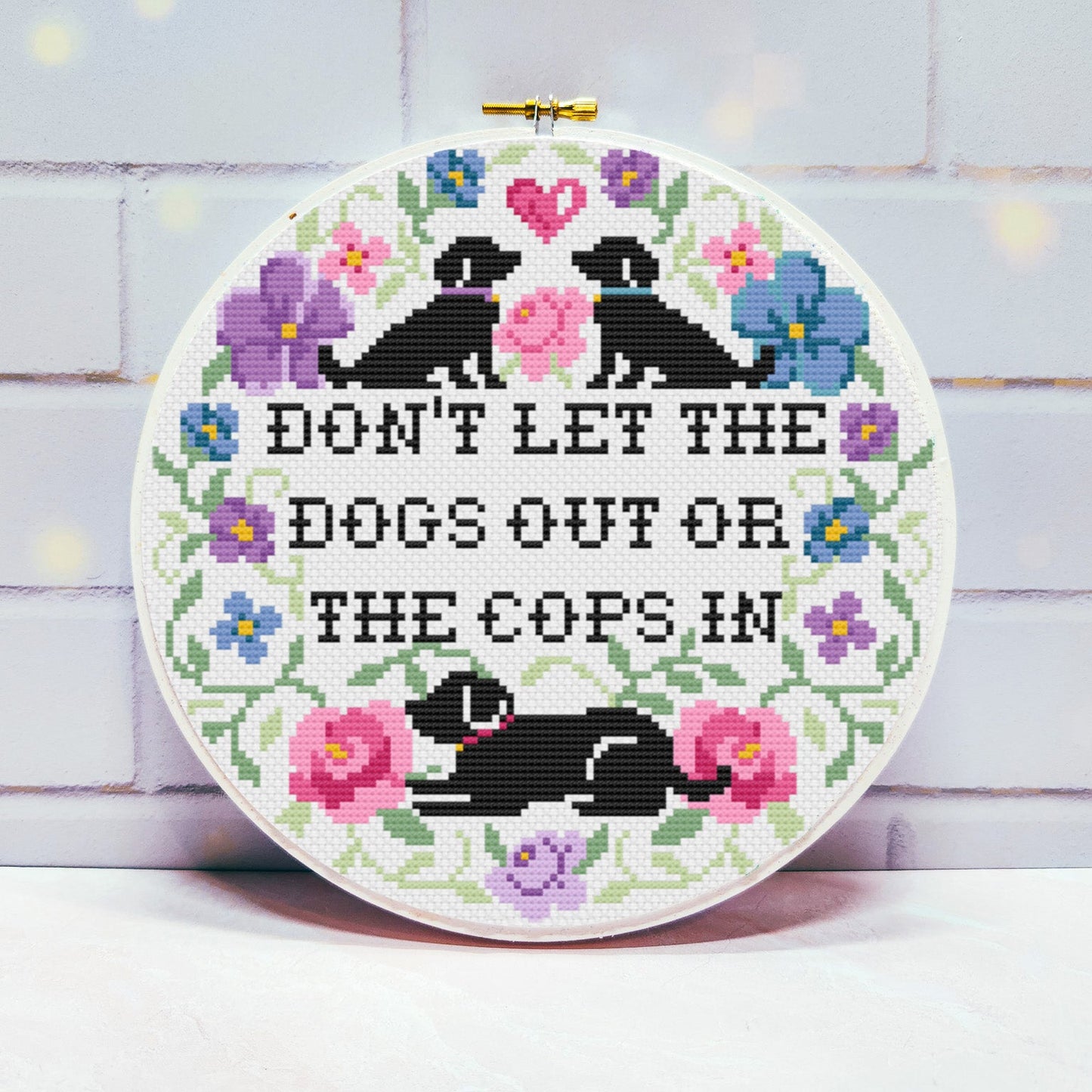 Cross-stitched hoop with dogs and flowers on a light background