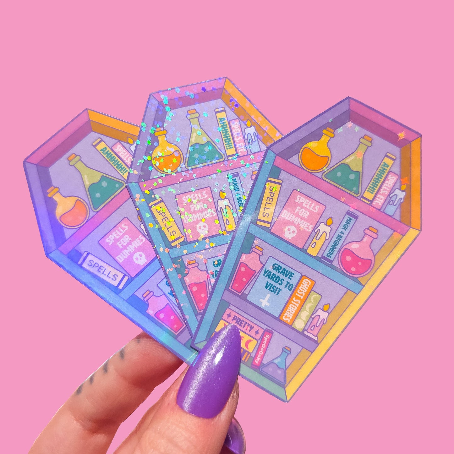 3 coffin shaped bookcase stickers with potion bottles and books on a pink background