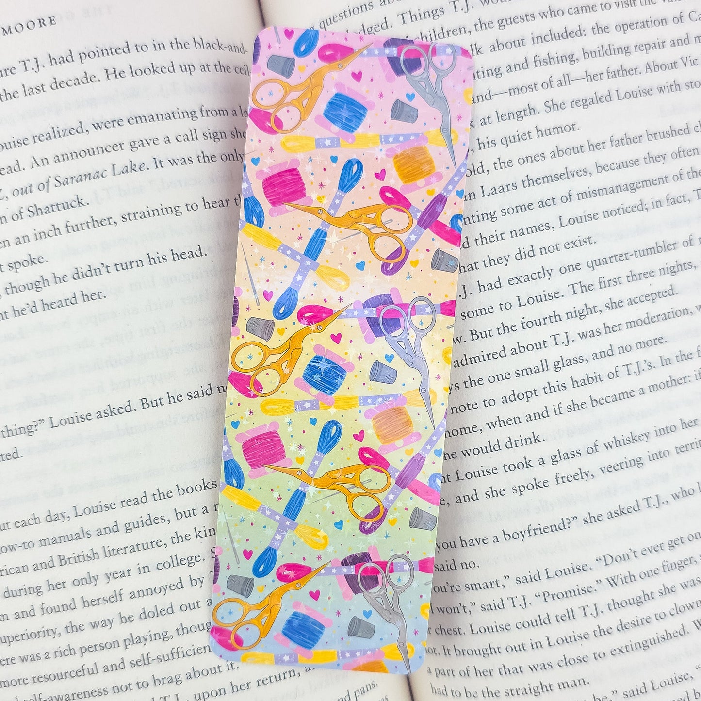 Embroidery holographic bookmark inside an open book – handmade laminated sewing supplies design with scissors, floss, and thimbles