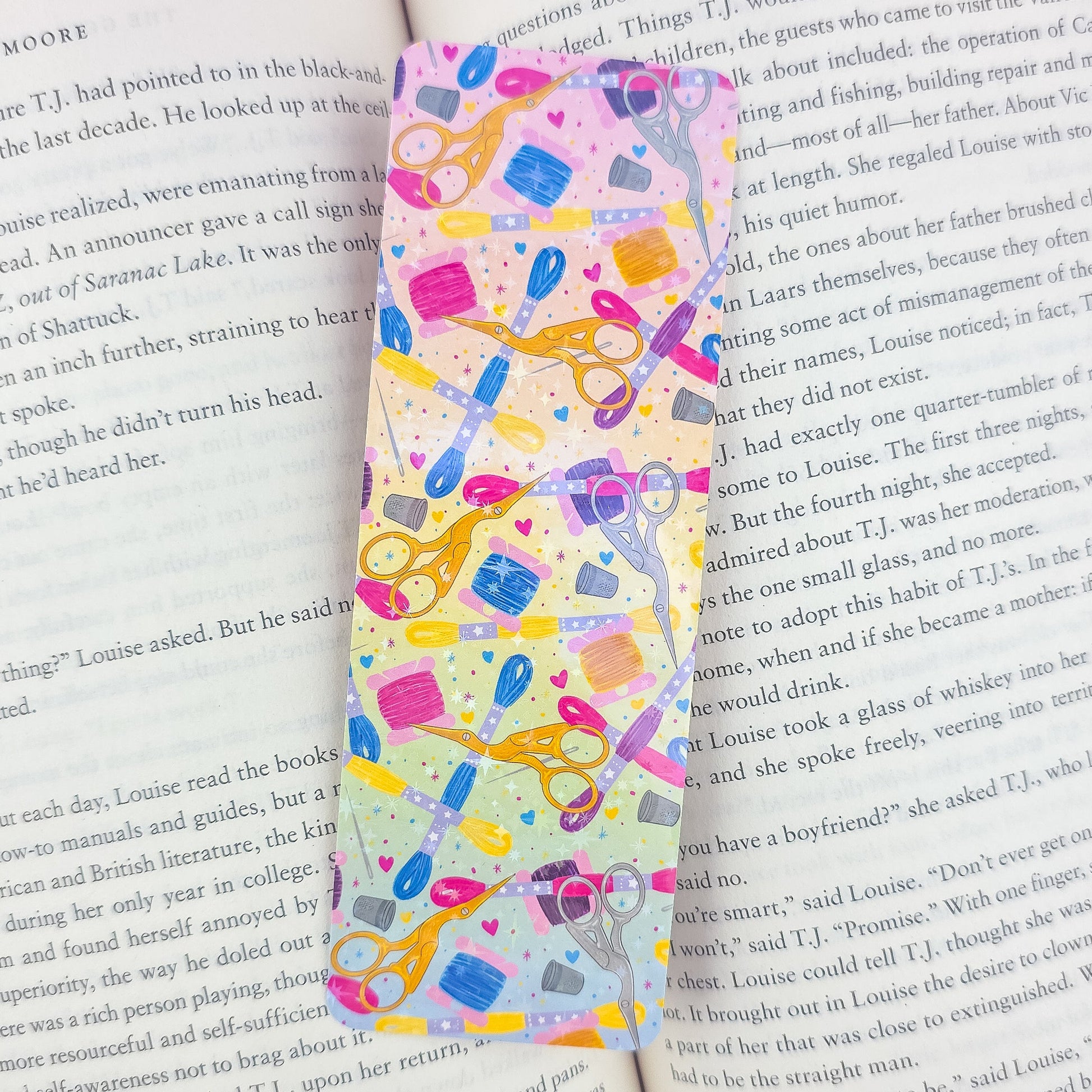 Embroidery holographic bookmark inside an open book – handmade laminated sewing supplies design with scissors, floss, and thimbles