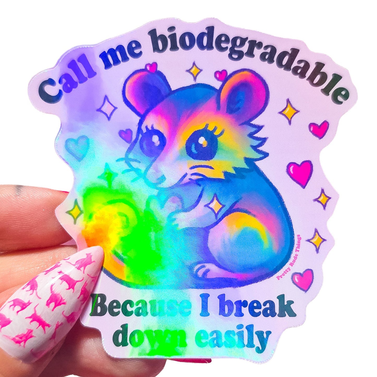 Colorful sticker with a cartoon possum holding a heart and text that says "Call me biodegradable because I break down easily" on a light pink background