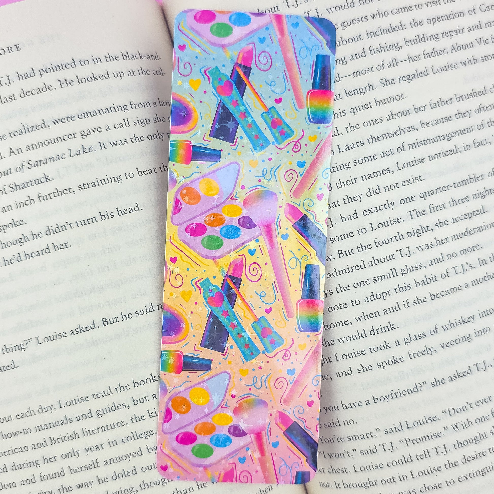 Makeup holographic bookmark placed inside an open book – colorful handmade gift for beauty lovers and readers