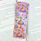 Holographic rainbow mushroom bookmark placed inside an open book, showing sparkly finish