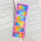 Pink bookcase holographic bookmark placed inside an open book – rainbow bookshelf design, handmade laminated book lover gift