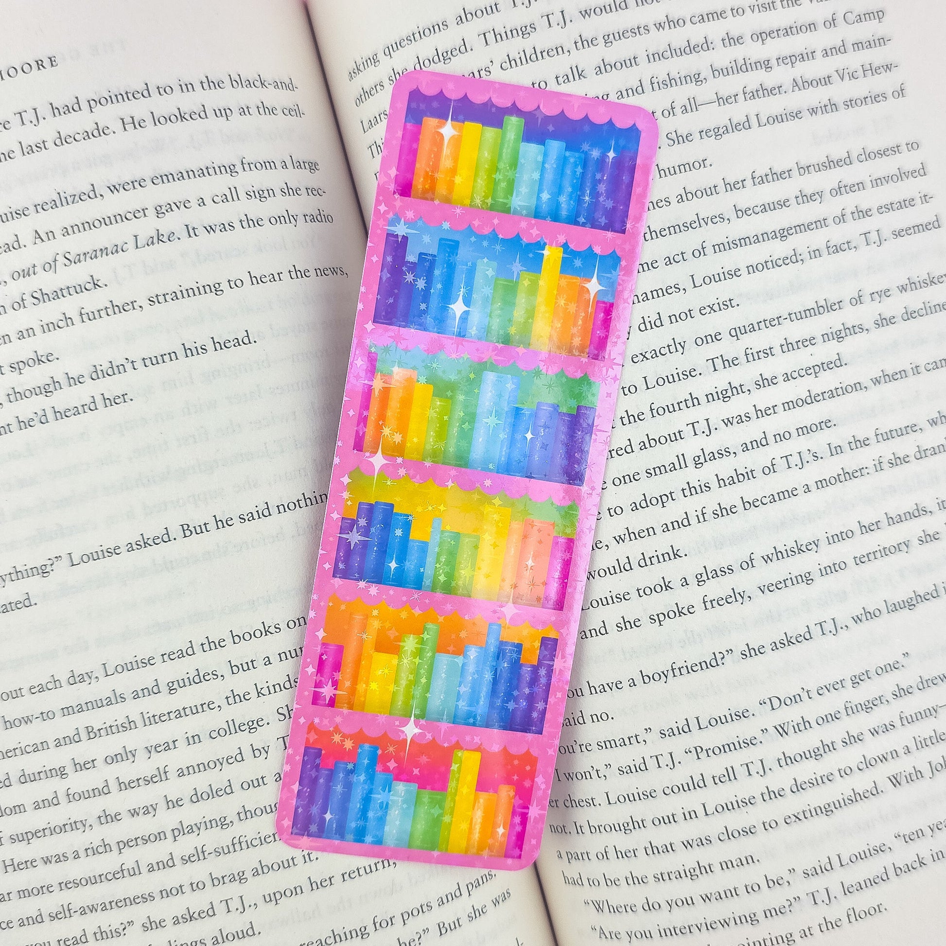 Pink bookcase holographic bookmark placed inside an open book – rainbow bookshelf design, handmade laminated book lover gift