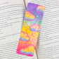 Rainbow holographic clouds bookmark placed inside an open book – cute colorful handmade gift for readers