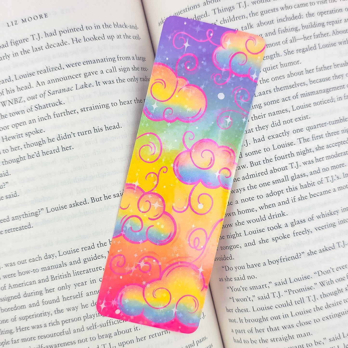 Rainbow holographic clouds bookmark placed inside an open book – cute colorful handmade gift for readers