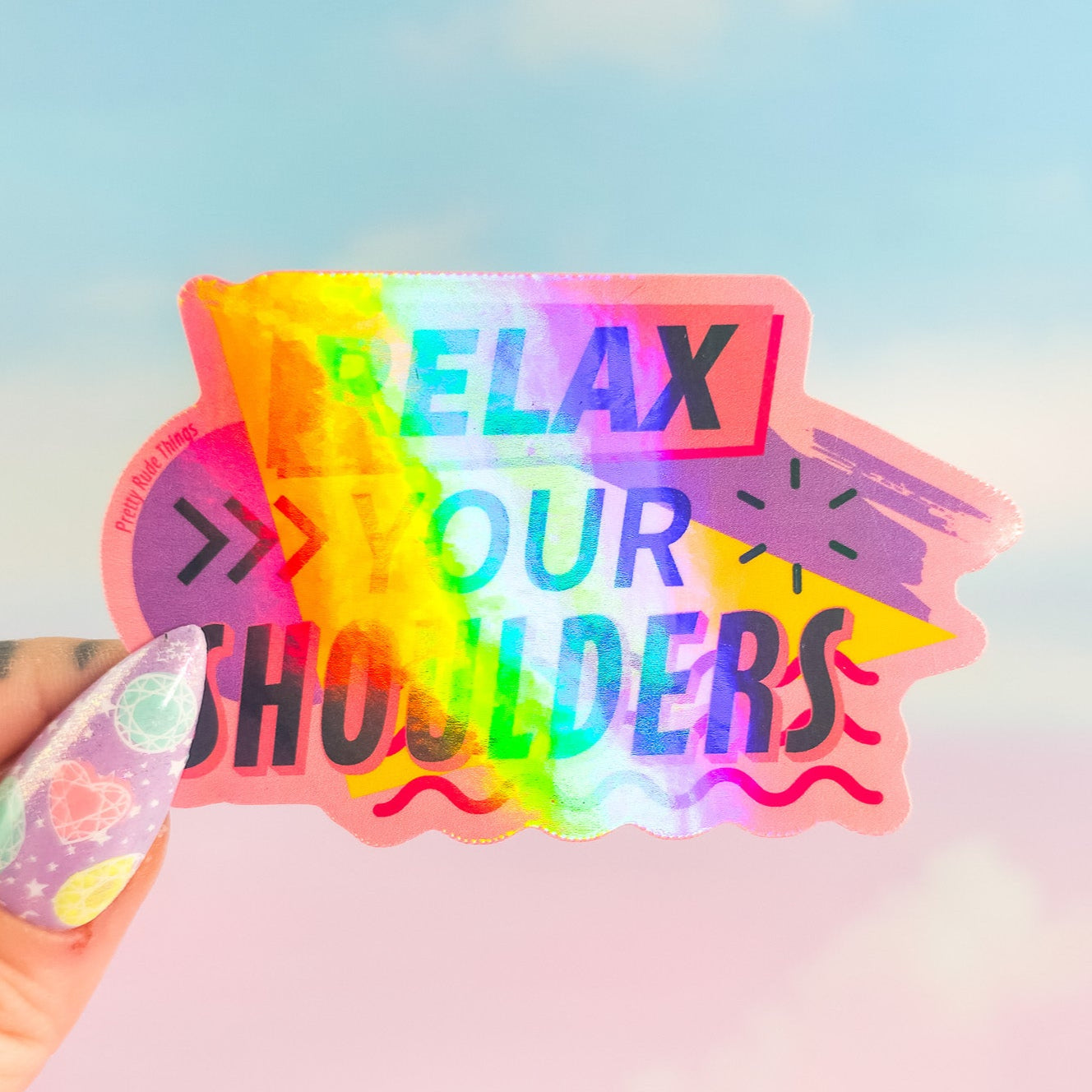 Holographic sticker with 'Relax your shoulders' text held by a hand against a blurred background