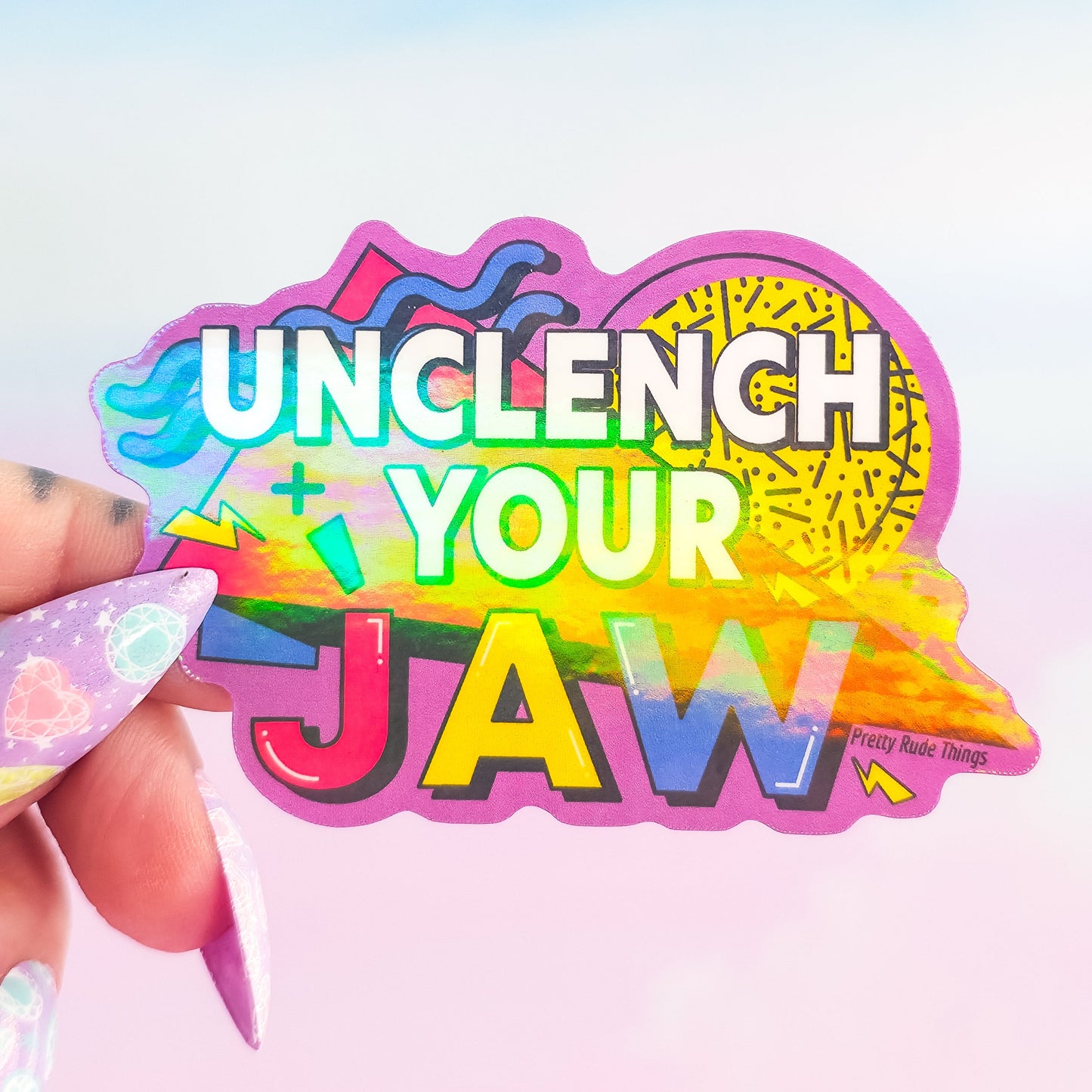 Colorful 'Unclench Your Jaw' sticker held by a hand with a blurred background